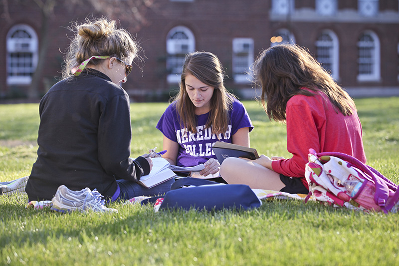 三个学生一起在草地上坐成一圈.