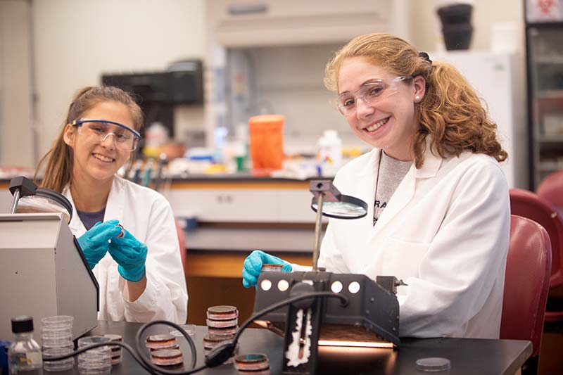 两个穿着实验室大褂的学生在微笑