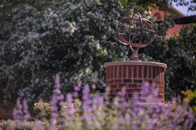 A decorative statue on Meredith's campus with flowering trees.