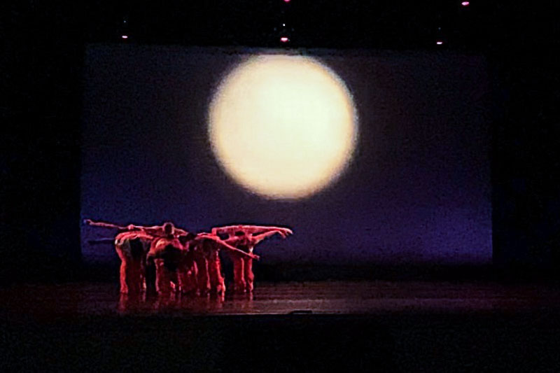 跳舞的学生在黑暗的舞台上穿着红色的衣服