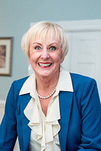  Linda Shields smiling in a white shirt and grey cartigan