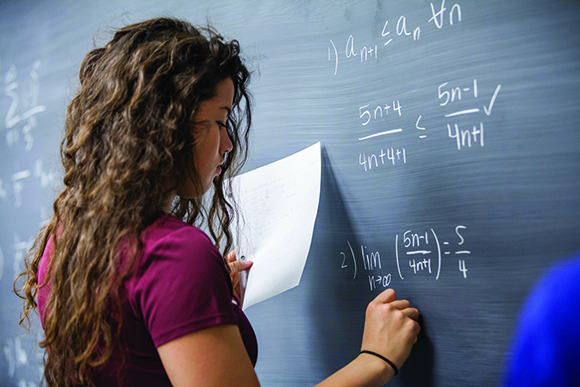 woman writing equations on a chalkboard