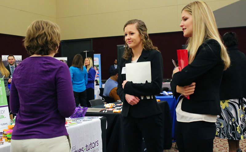 Students at a career fair speaking to a recruiter