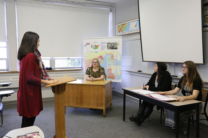 A student presents to her professor and two classmates during Moot Court class