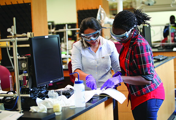 two female student in a chemistry lab reading a book