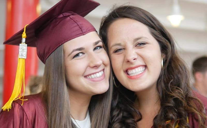 two Meredith graduates in caps and gowns