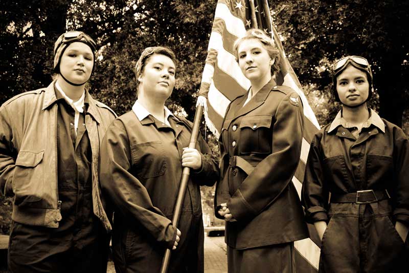 Actresses in pilot uniforms holding the flag