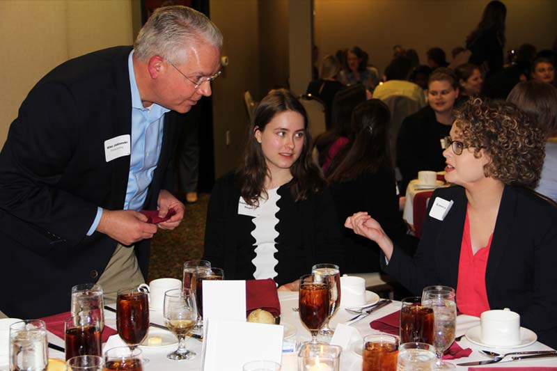 Two Meredith students networking with a working professional during the Networking and Etiquette Dinner