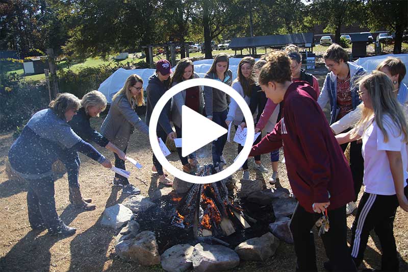 click on image of students burning papers to see video in modal showing An Exercise in Forgiveness