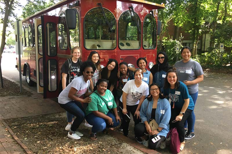 International Students posing on trip in front of a trolley
