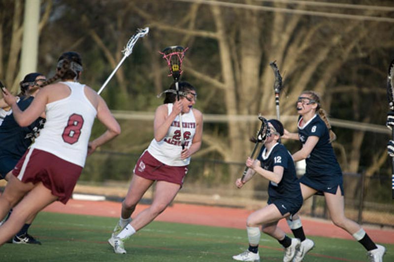 Photo shows a lacrosse game with two players from each team