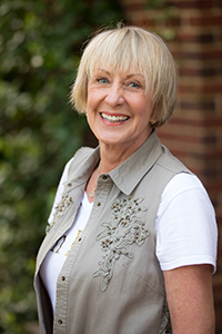  Linda Shields smiling in a white shirt and grey cartigan