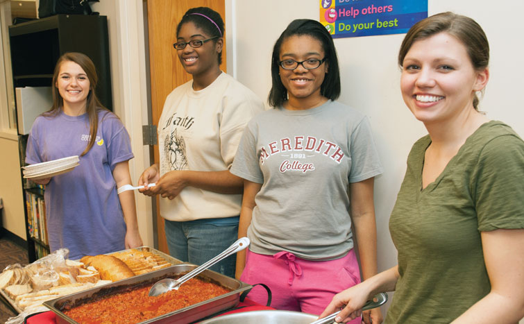 Four Meredith students volunteer by serving food. 