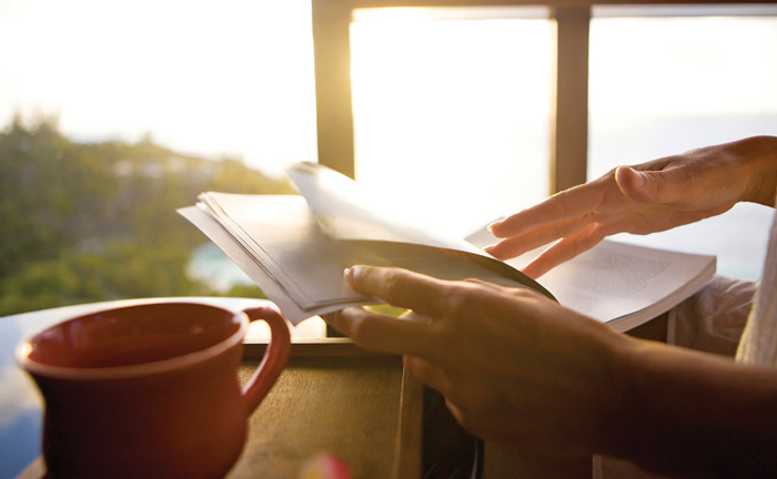 reaching for book with coffee in hand