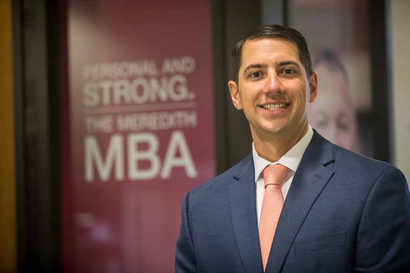 MBA alumnus Matthew Evans in front of sign that says Personal and Strong. The Meredith MBA
