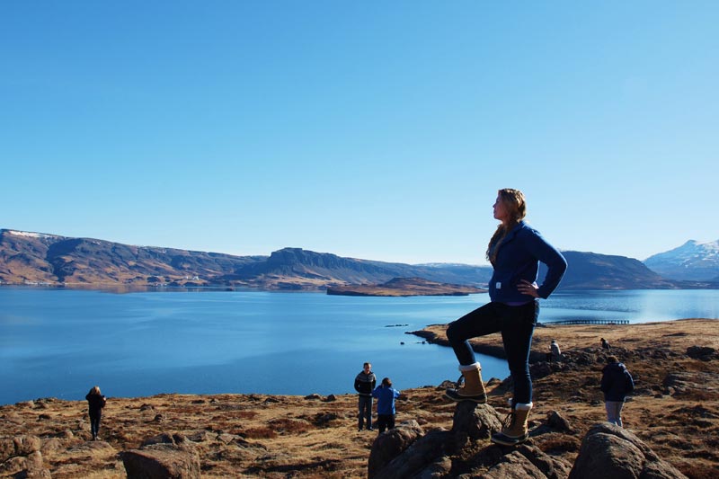 Student standing on rock overlooking lake.
