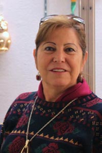  Monica Ruiz posing in colorful sweater with ornaments visible in background