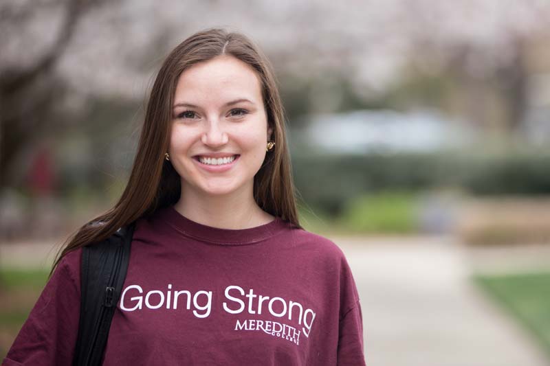 Image of Rachael Nicholos wearing a sweatshirt with the words Going Strong Meredith College