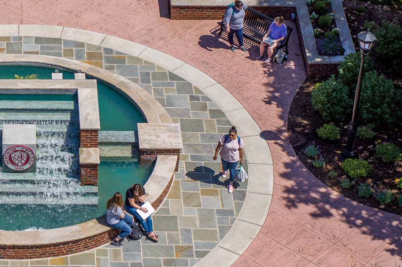 Students seated around the Beam Fountain in front of Johnson Hall