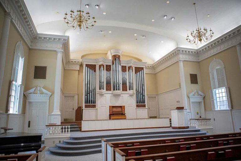 Image of the inside of the Chapel. The view is from the middle of the pews to the side looking at the alter and organ.