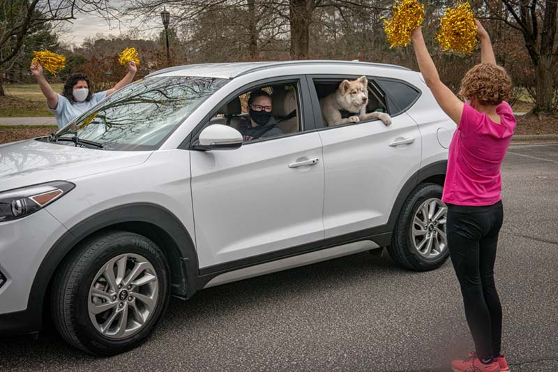 Education Faculty with Pom Pom welcoming new student in car