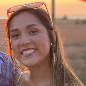 Malia Garber smiling at the camera in front of a sunset.