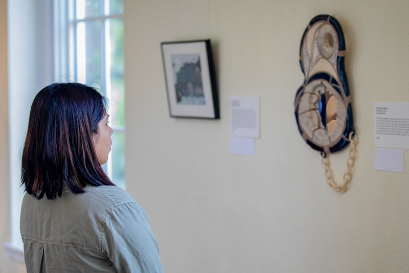 A woman studies the student art hanging on the wall in Johnson Hall.