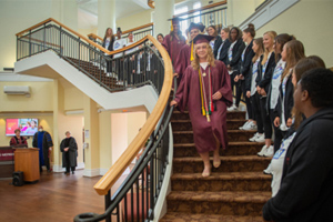 senior lacrosse players descend steps in Johnson Hall flanked by the lacrosse team as part of a special commencement ceremony.