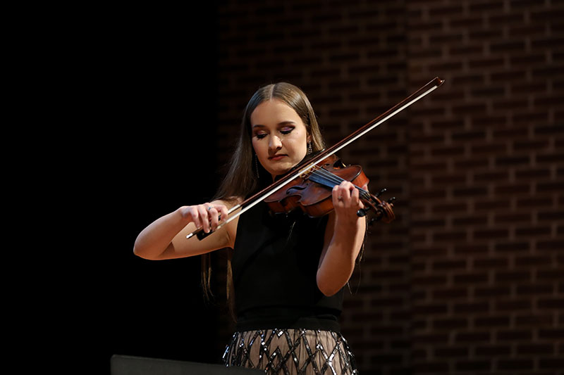 A student plays violin at a concert.