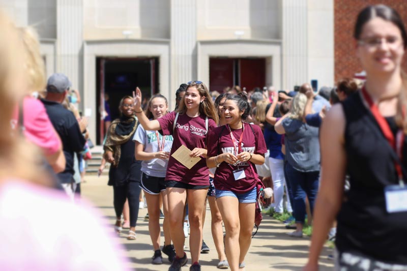 New Meredith students walking out of Jones Auditorium waving and smiling at parents on Move In Day.