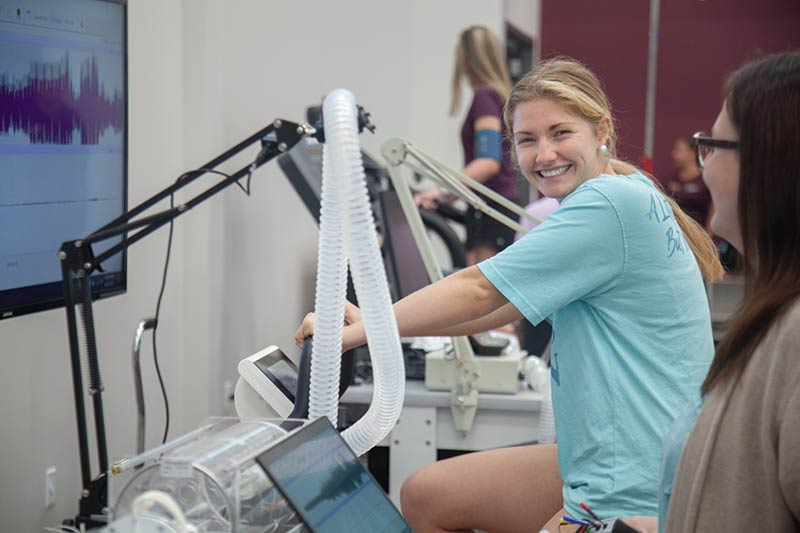 A student smiles while trying out new fitness equipment in the CHESS building.