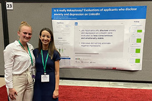 Two students in front of a posterboard for research.