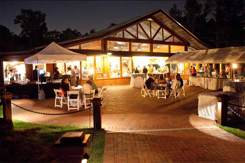 A back view of the angus barn pavilion with vendors, tables, and people eating and celebrating.