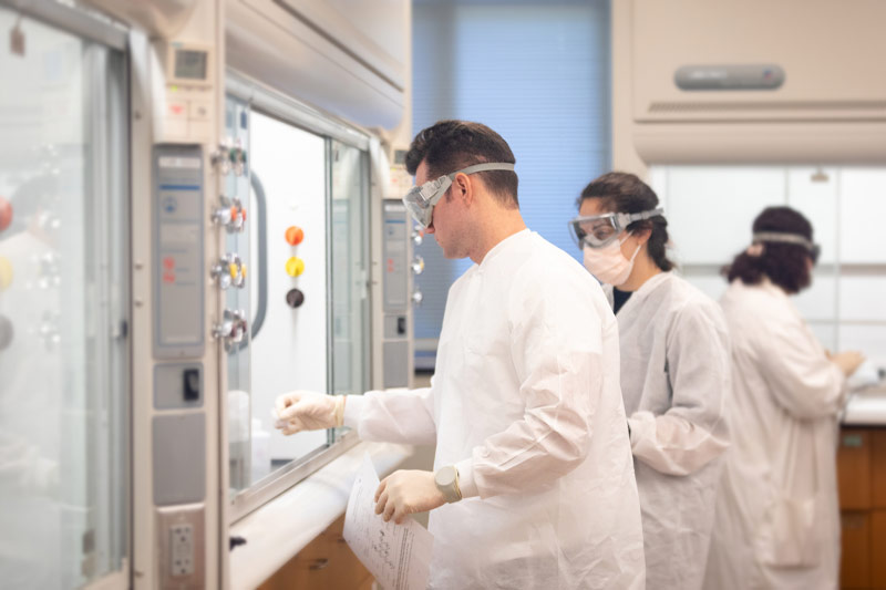 Three students in white lab coats in a science lab