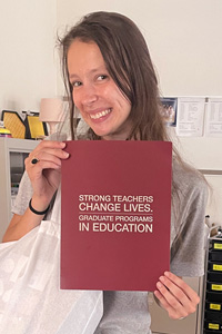 New Teacher holding a Meredith graduate education information packet