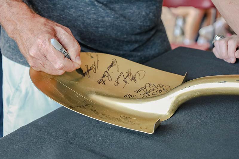 People sign a golden shovel at the athletic complex groundbreaking.