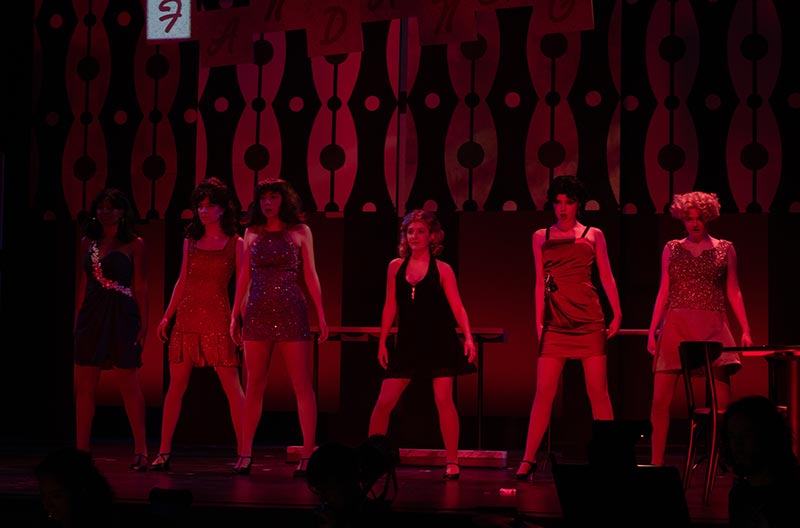 Theatre Performance showing six actors on stage in red tinted light