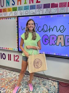 New 3rd Grade Teacher Sara Perry holding Meredith bag with school supplies.