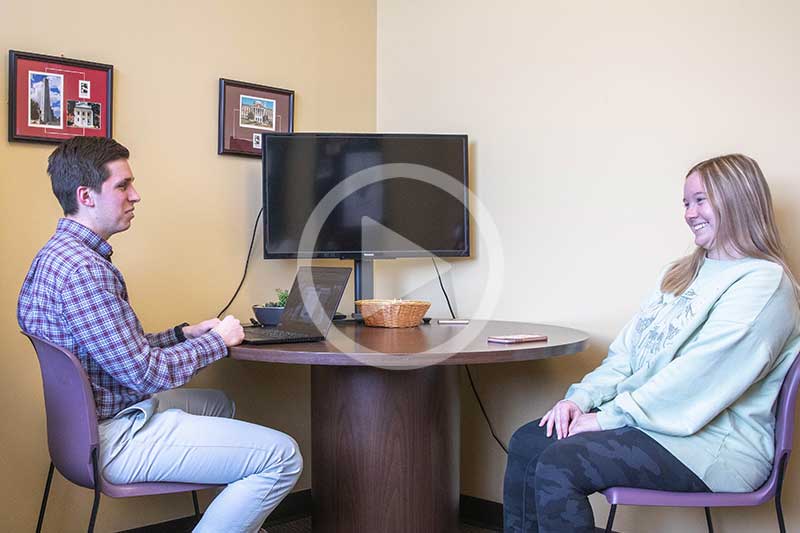 Student Success Center Explainer Video Image showing success coach and student talking at desk. 